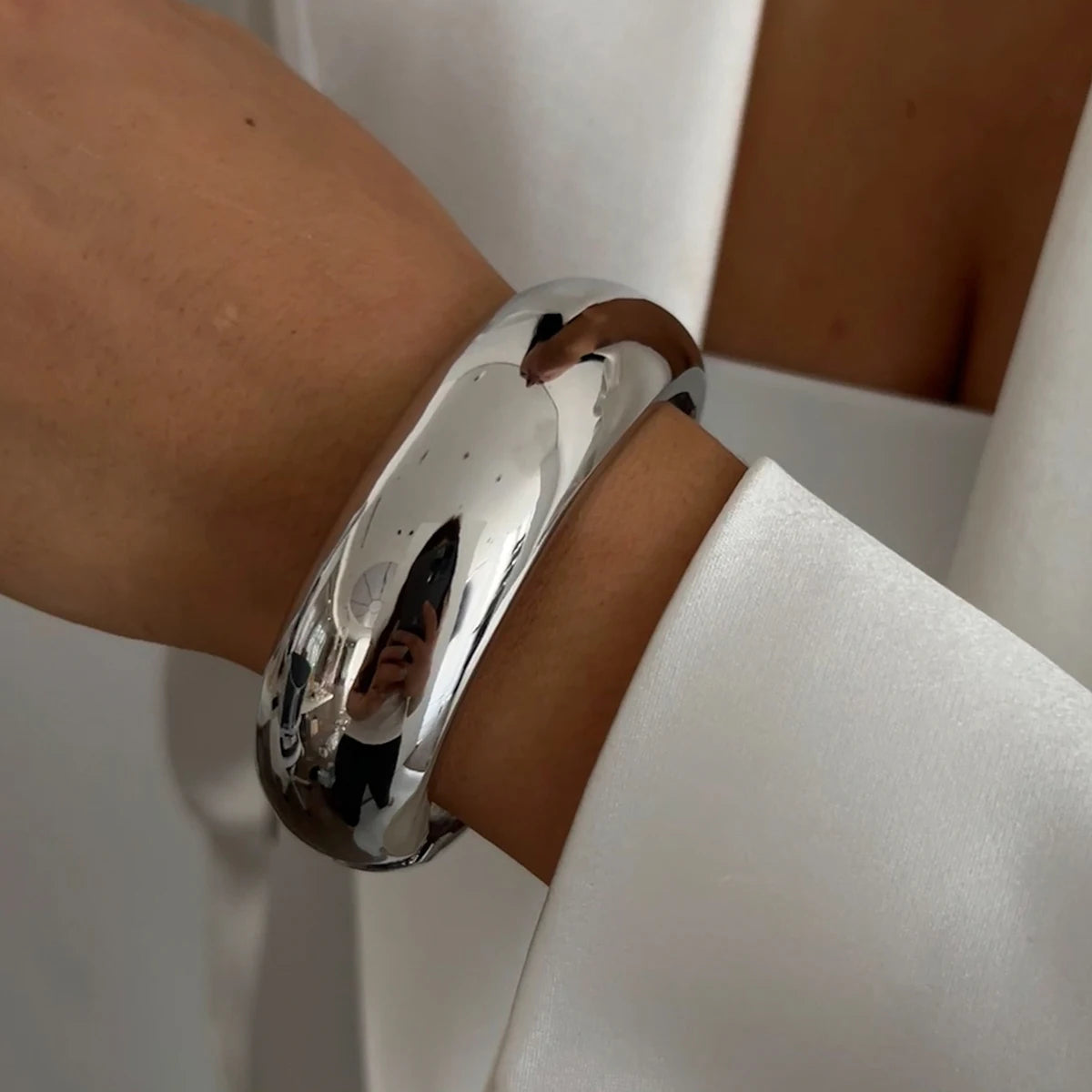 Silver bracelet on a wrist with a neutral background