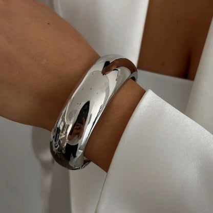 Silver bracelet on a wrist with a neutral background