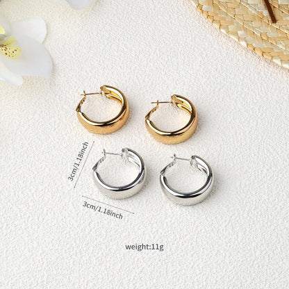 Two pairs of chunky hoop earrings shown on a textured white surface: one pair in polished gold and one pair in polished silver. Black measurement lines and text indicate 3cm/1.