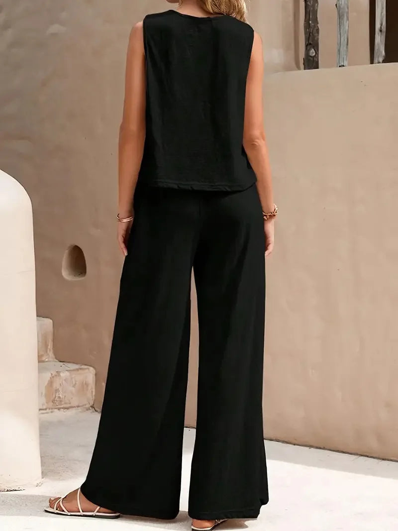 Person wearing a black sleeveless top and wide-leg pants in an outdoor setting.