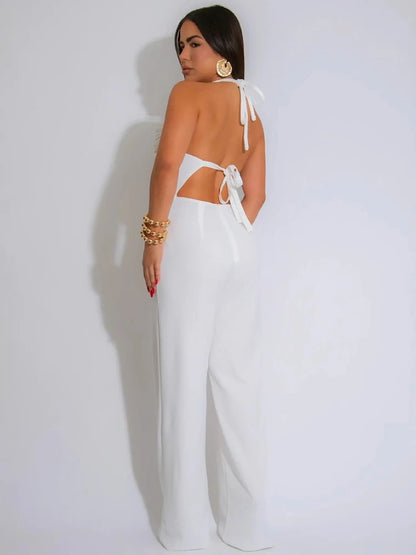 Woman wearing a white jumpsuit with a backless design on a plain background