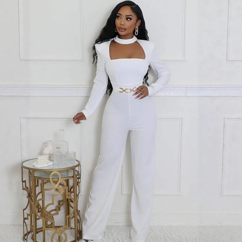 Woman in a white outfit standing in a stylish room with a gold side table.