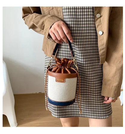 Person holding a drawstring bag with a plaid skirt and beige jacket.
