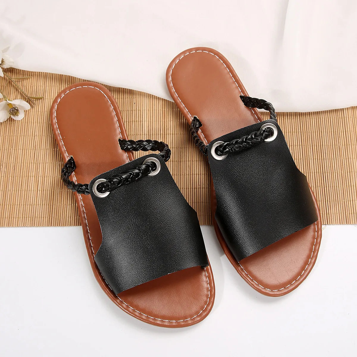 Pair of black sandals with brown soles on a white background