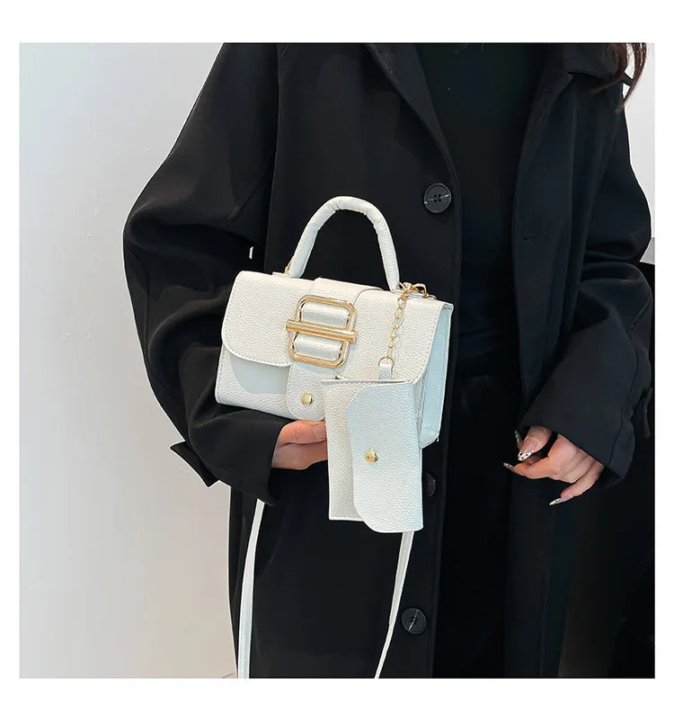 Person holding a white handbag with gold accents against a plain background