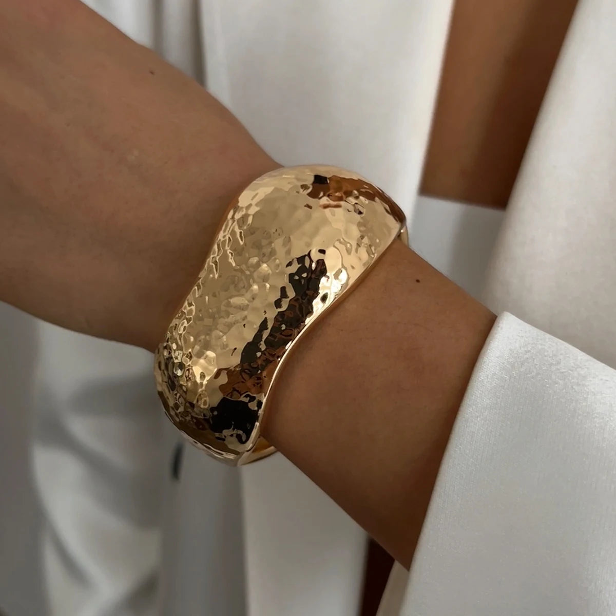Gold bracelet on a wrist with a blurred background