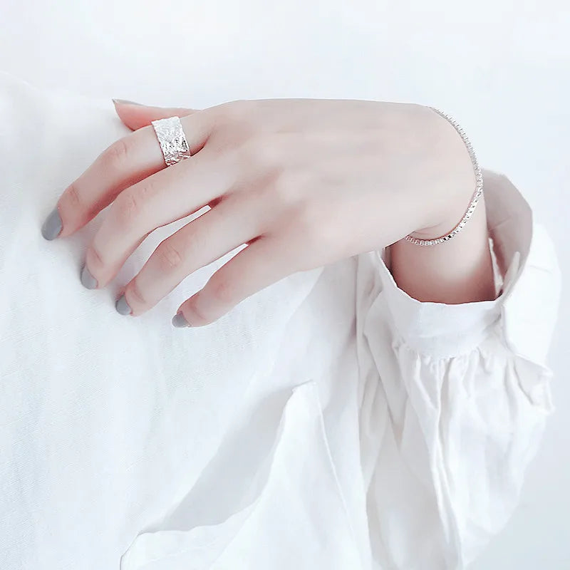 Hand wearing a silver ring and bracelet on a white background