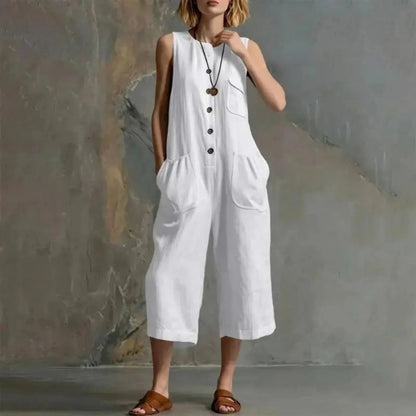 A woman models a white sleeveless linen-look jumpsuit with front buttons and large patch pockets, standing against a textured gray wall. The brand name 'XJGOOD' is printed in black in the top-left corner.