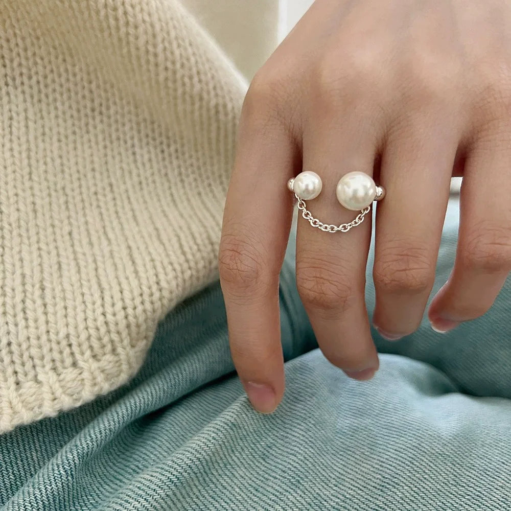 Hand wearing a pearl ring with a soft background