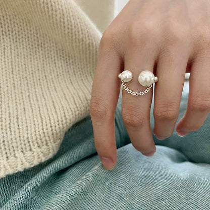Hand wearing a pearl ring with a soft background