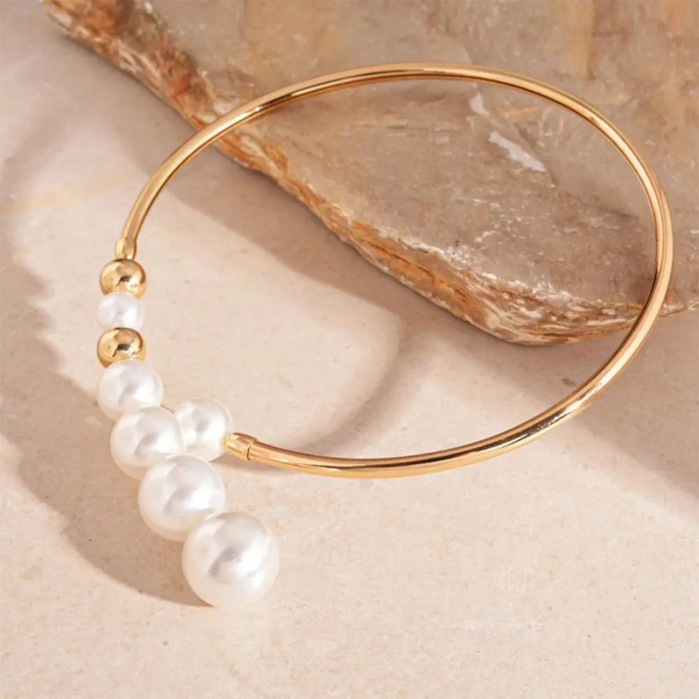 Gold bracelet with pearls on a beige stone background