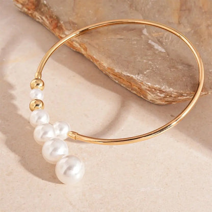 Gold bracelet with pearls on a beige stone background