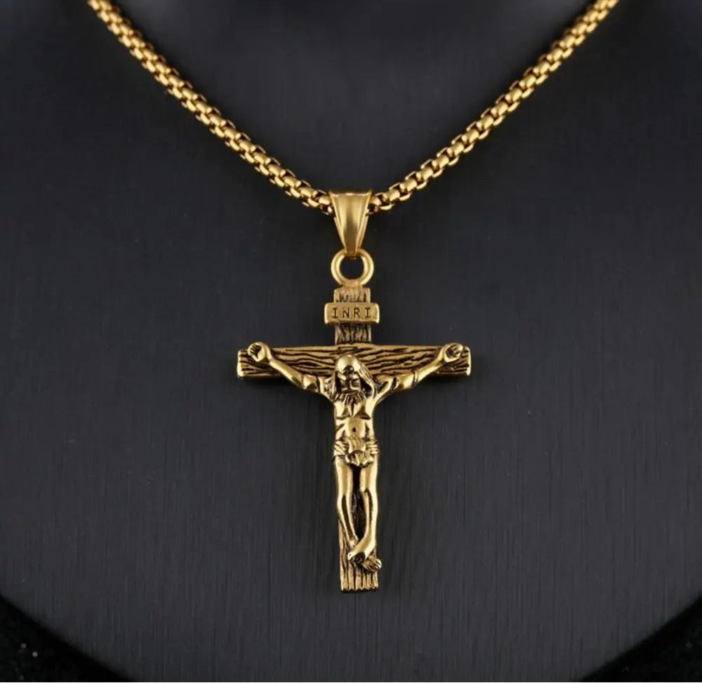 Gold crucifix pendant on a chain against a black background