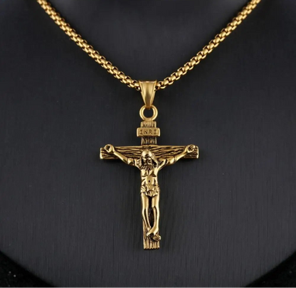 Gold crucifix pendant on a chain against a black background