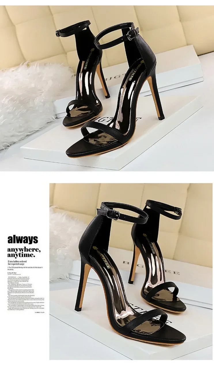 Black high-heeled sandals on a white surface with a beige background