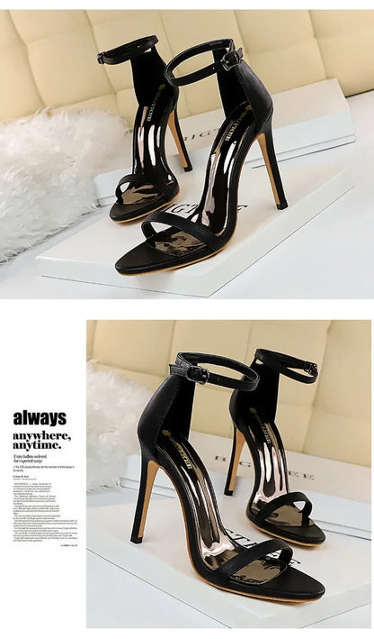 Black high-heeled sandals on a white surface with a beige background
