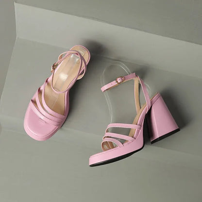 Pair of pink high-heeled sandals on a light gray background