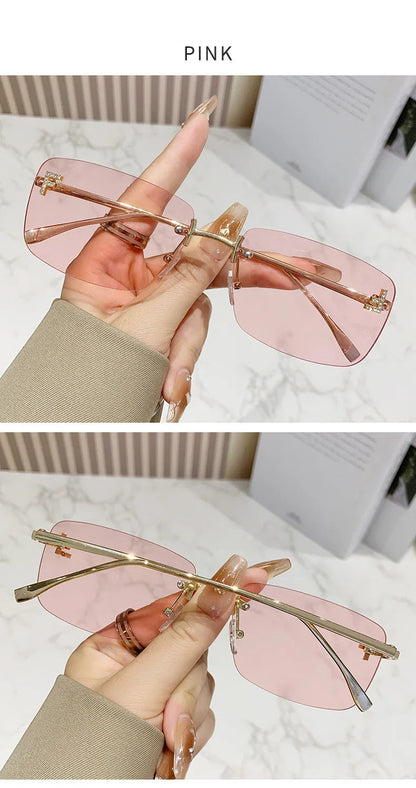 Pink sunglasses held by a hand with a blurred background