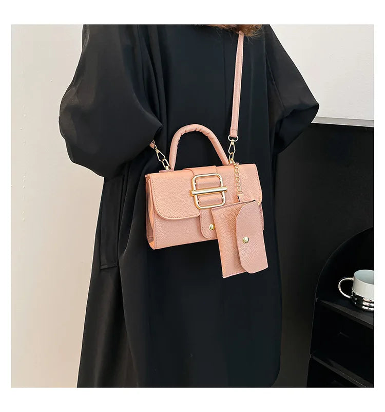 Pink handbag with gold accents held by a person wearing a black coat.
