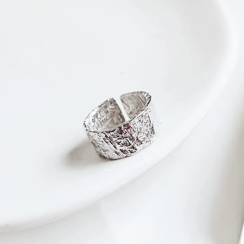 Silver ring with textured design on a white background