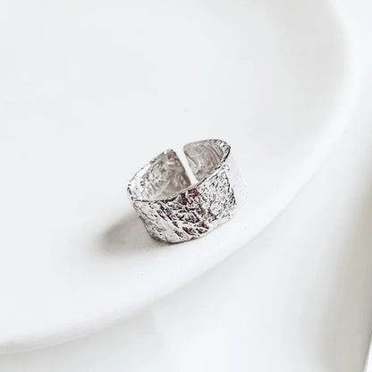 Silver ring with textured design on a white background