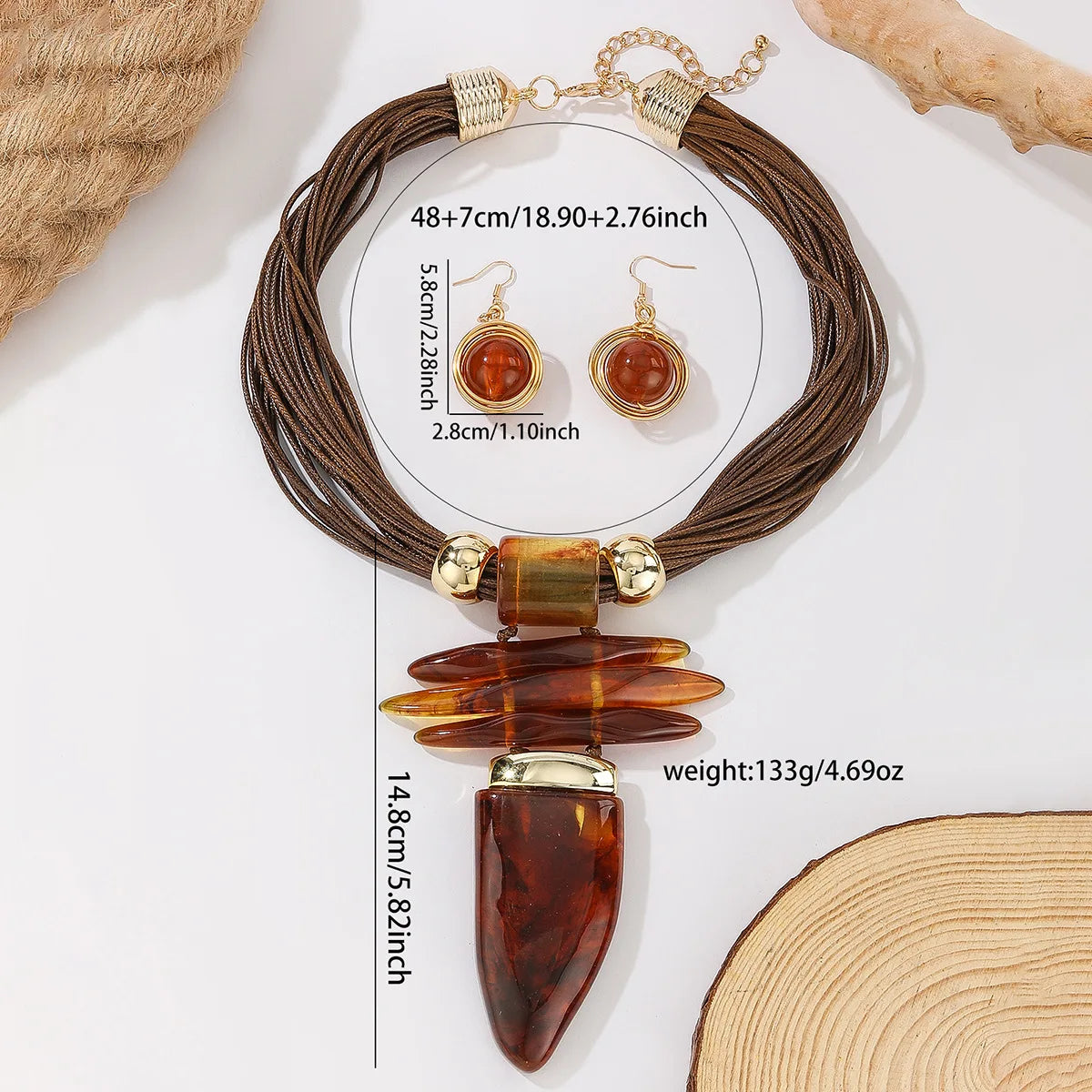Brown multi-strand cord necklace with a large amber-brown teardrop pendant and gold-tone hardware, shown on a white background with size measurements and a matching pair of drop earrings.
