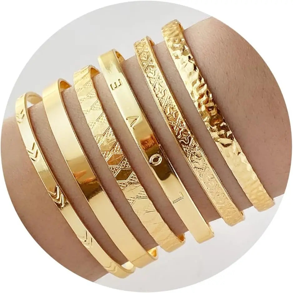 Set of gold bracelets with various patterns on a white background