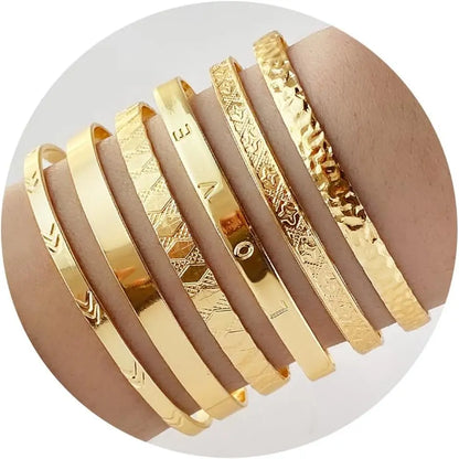 Set of gold bracelets with various patterns on a white background