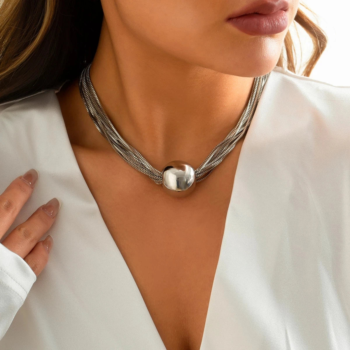 Silver-tone layered chain statement necklace featuring multiple slender strands and a polished rounded metal centerpiece.