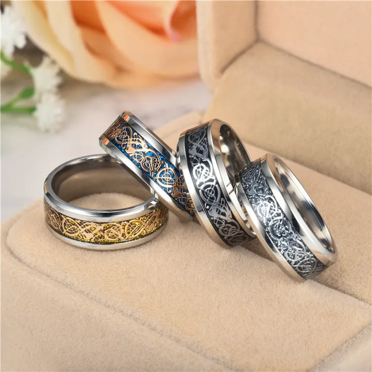 Three silver rings with intricate designs on a beige surface.