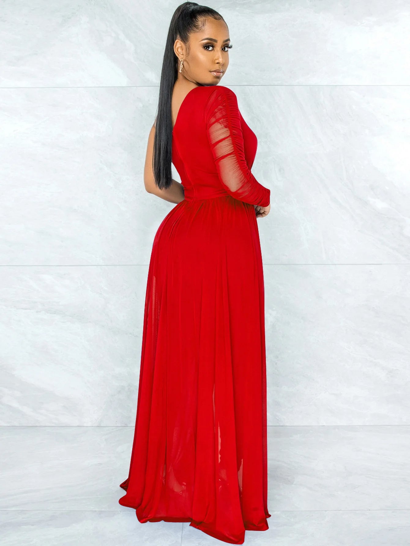 Woman wearing a red dress with sheer sleeves against a white background
