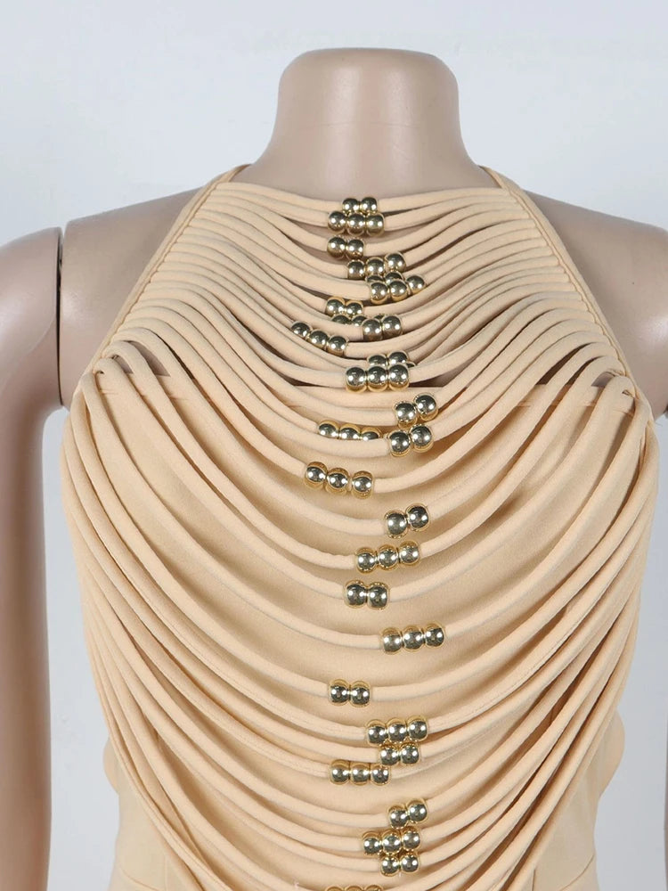 Beige draped garment with gold embellishments on a mannequin against a white background