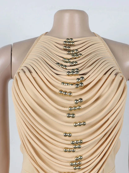 Beige draped garment with gold embellishments on a mannequin against a white background