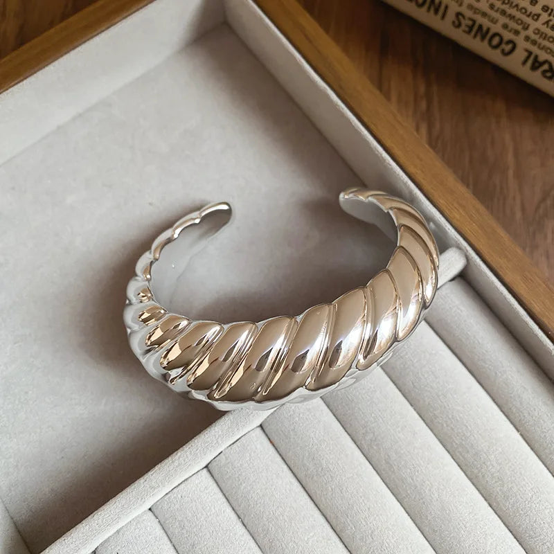 Silver bangle on a soft surface with a wooden background