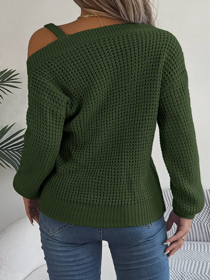 Green knitted sweater with cut-out shoulder design worn by a person, against a neutral background.