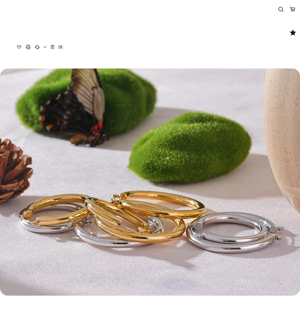 Gold and silver rings on a white surface with green moss and a butterfly.