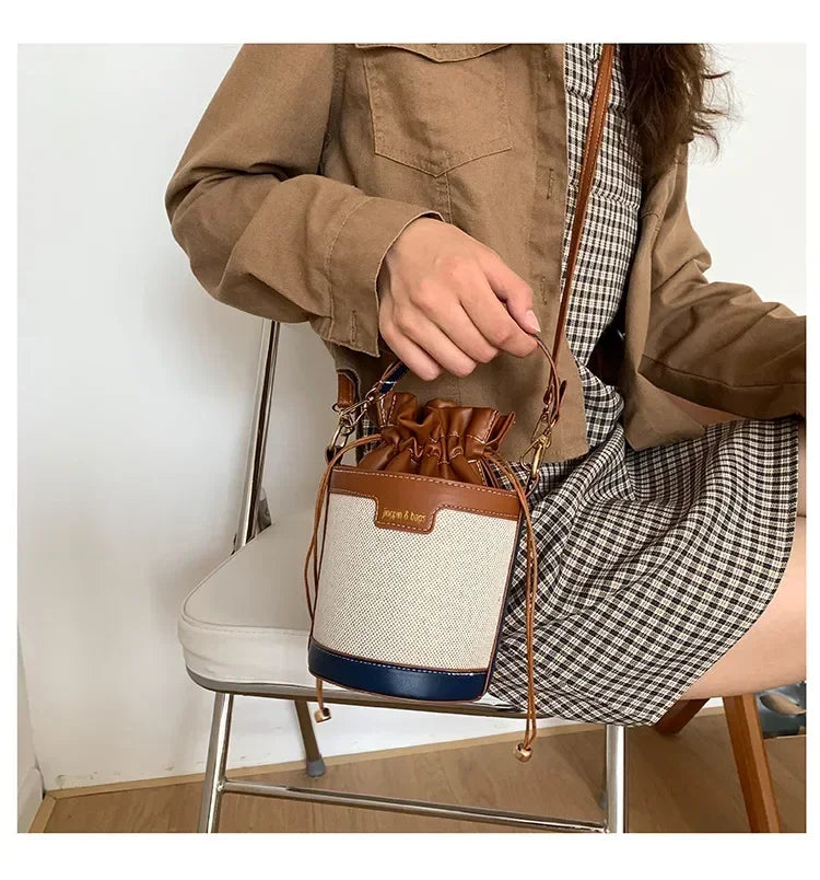 Person holding a brown and beige handbag with plaid shirt and jacket