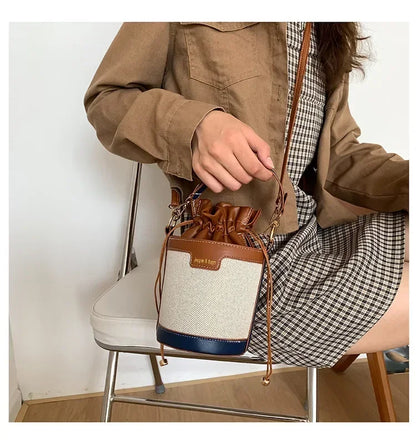 Person holding a brown and beige handbag with plaid shirt and jacket