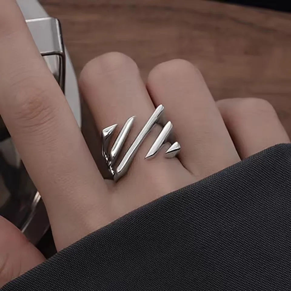 Silver ring with a unique design worn on a finger against a neutral background