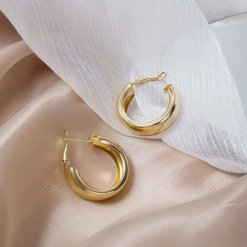 Gold hoop earrings on a soft fabric background