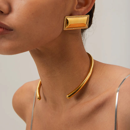 Gold collar necklace worn by a person on a neutral background