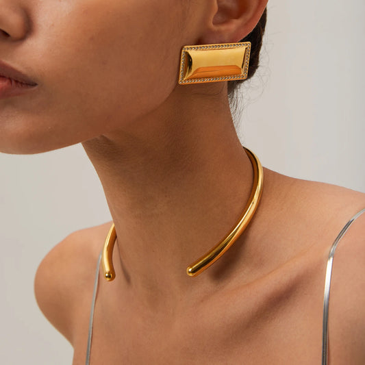 Gold collar necklace worn by a person on a neutral background