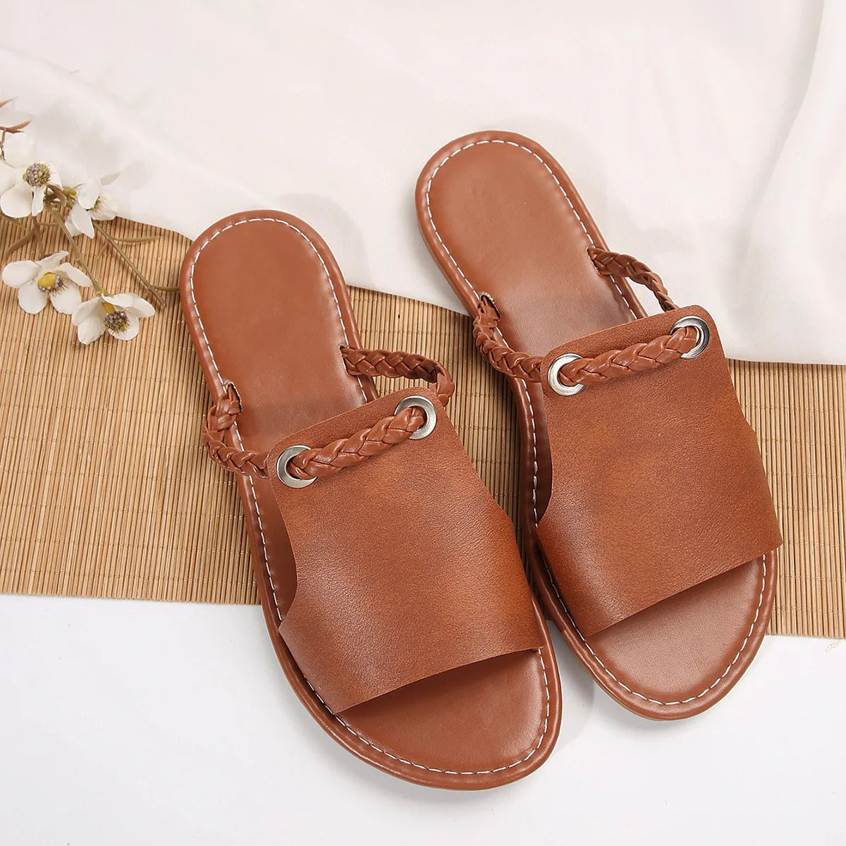Pair of brown sandals with braided straps on a white background