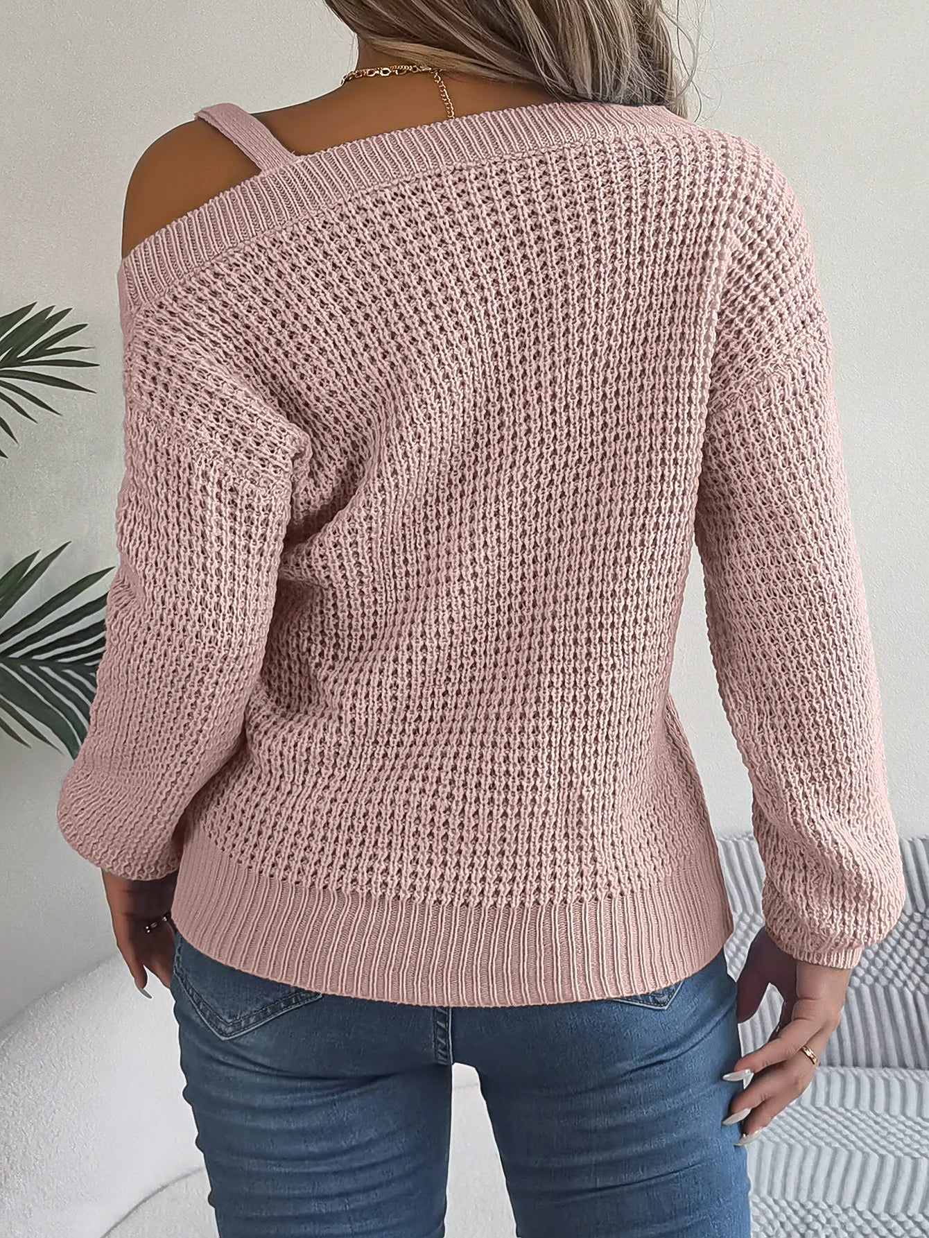 Pink knitted sweater worn by a person with a neutral background