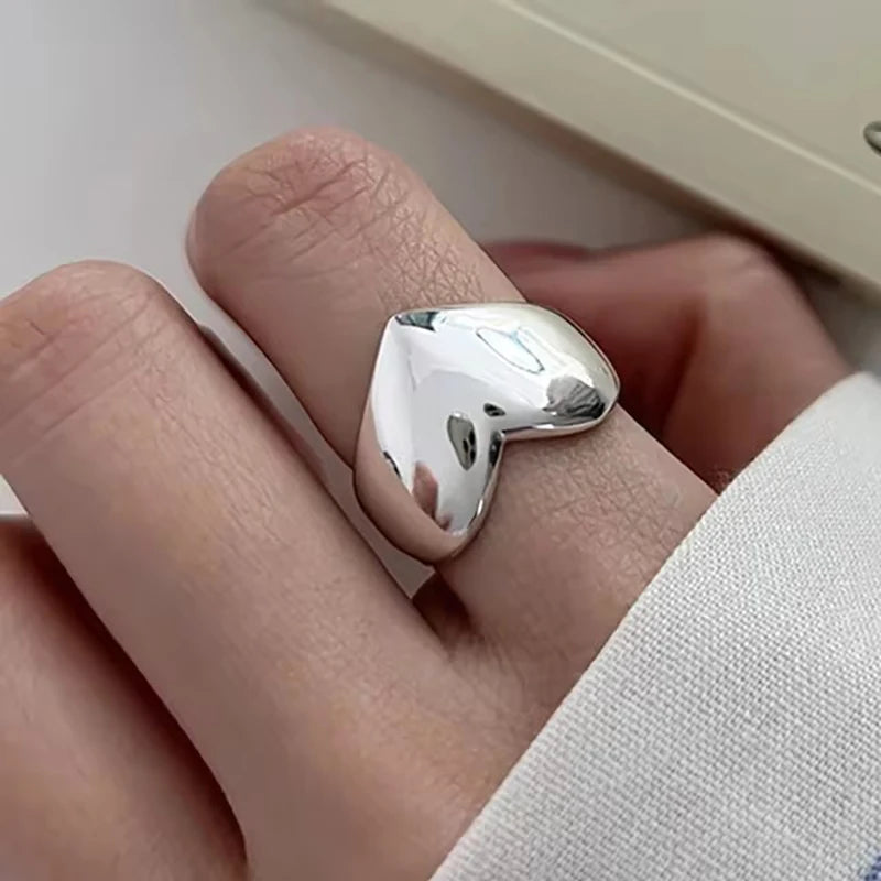 Silver ring on a finger against a neutral background
