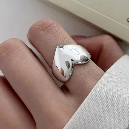Silver ring on a finger against a neutral background