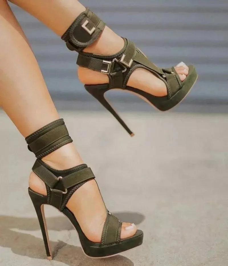 Green high-heeled sandals with strap details on a blurred background