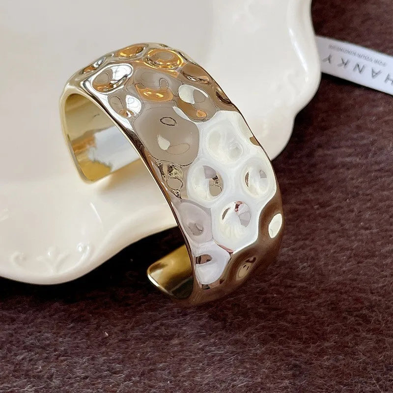 Gold ring with textured design on a white ceramic dish