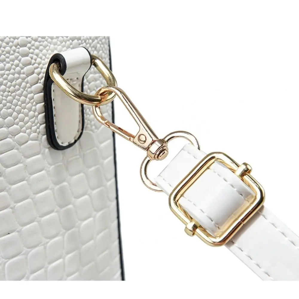 White leather strap with gold hardware attached to a white textured surface