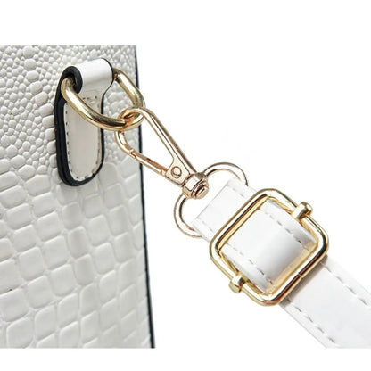 White leather strap with gold hardware attached to a white textured surface